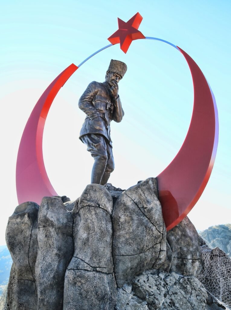 man in black jacket and pants holding red umbrella statue