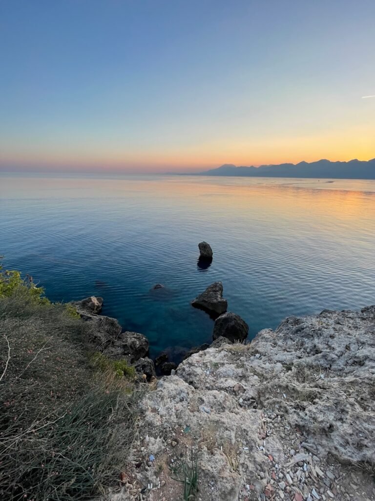 a body of water sitting next to a rocky cliff