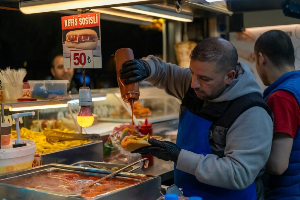 a man is making a hot dog at a hot dog stand